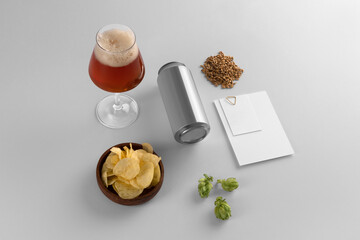 Blank beer can, glass with beer, cards, hops, chips, malts on a white background, craft beer mockup...