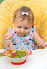 Baby is eating vegetable puree. Selective focus.