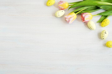 Fototapeta na wymiar Easter background with space for text or product, pink yellow tulips and decorative eggs.