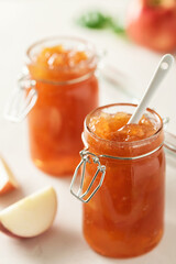Apple jam in a glass jar. Apple jam on a light background. Delicious natural marmalade.
