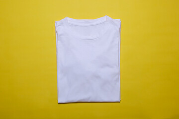 Folded white t-shirt mockup on yellow background. Flat lay tee template