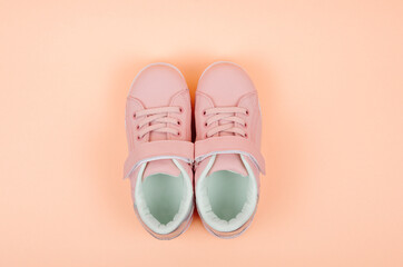 Cute pink children's sneakers. Orange background. Baby clothes and shoes. Flatlay