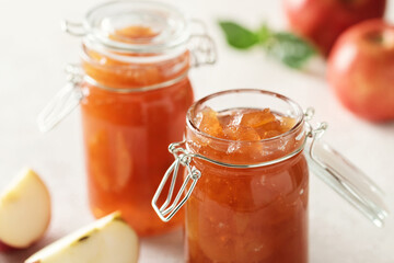 Fototapeta na wymiar Apple jam in a glass jar. Apple jam on a light background. Delicious natural marmalade.