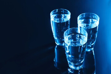 Glasses of vodka on dark table, space for text