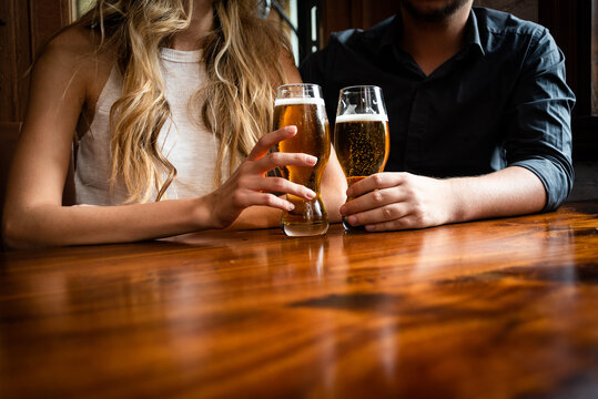 Beer in the bar. A man and a woman sitting at the table with two glasses with draft beer toasting in a pub