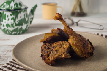 Fried duck on brown plate and napkin against white rustic table and background