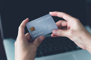 woman holding credit card with laptop on background. paying by credit card, online shopping concept.