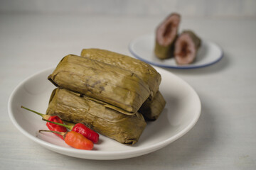 Red rice lontong or rice cake with spicy beef floss filling. Lontong or Rice cake is Indonesian dish made of compressed rice cake in the form of a cylinder wrapped inside a banana leaf then steam it.