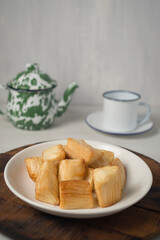 Fried marinated cassava on white plate with teapot and tea cup. One of traditional dish that very popular in Indonesia 