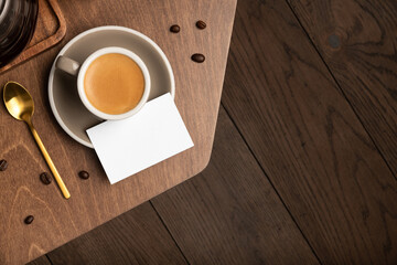 Blank business card on a wooden table, with coffee cup, espresso, copper spoon on a wooden...