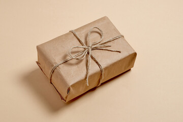 eco gift box with twine bow. ready-made wrapped kraft paper gift on beige background