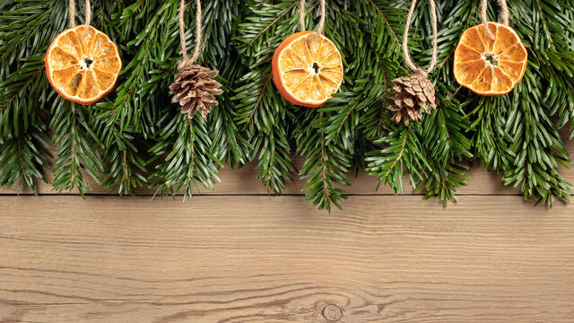 Zero waste and eco friendly christmas concept. Christmas tree branches with natural decorations on a wooden wall. Horizontal banner with copy space