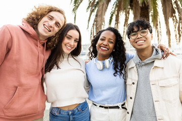 Portrait of united millennial group of friends outdoors - Smiling young students people hugging each other while having fun together on holidays in city street - Youth and friendship concept