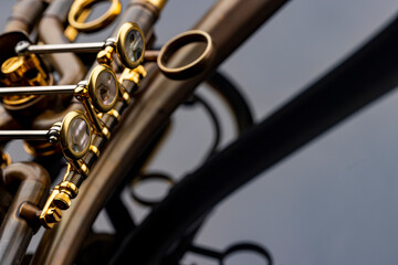 Fototapeta premium A rotary type trumpet with a curved leadpipe in matte brown with gold elements and pearl type buttons on a reflective surface
