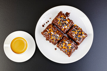 Homemade brownie and cups of coffee espresso on dark table. Top view.