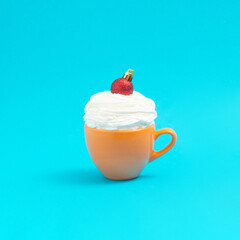 In the yellow coffee salt with whipped cream, a red Christmas decoration was placed. Minimal idea xmas. New Year 2022.
