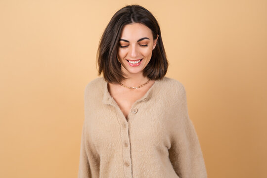 Young woman on a beige background in a soft cozy sweater with daytime professional make-up cute smiling