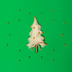 Wealth Christmas composition. Green background. Wooden and white Christmas tree. Small golden balls as decoration. Asymmetrical arrangement of golden balls. Law of attraction and growth.