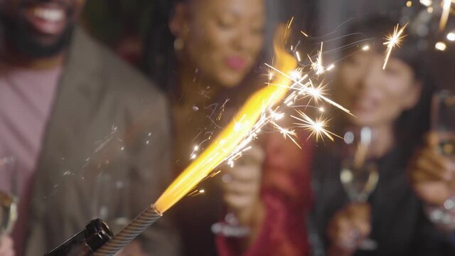 Close Up of Sparklers with Friends Celebrating with Champagne