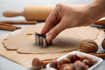 Woman making gingerbread man with cutter at table, closeup. Homemade Christmas biscuits