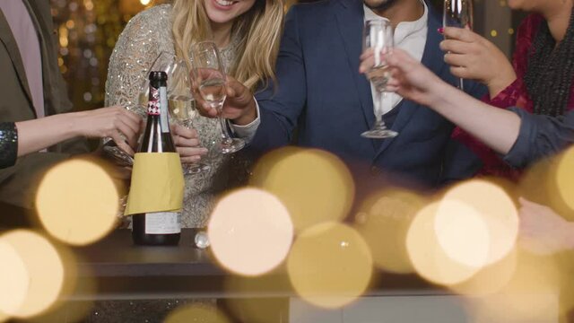 Mid Section Friends Toasting Champagne During New Years Celebrations In a Bar