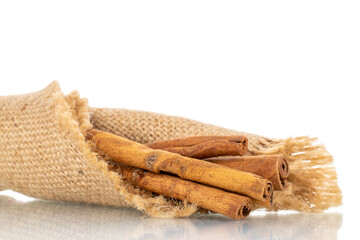 Several fragrant dry cinnamon sticks on a jute napkin, close-up, isolated on white.