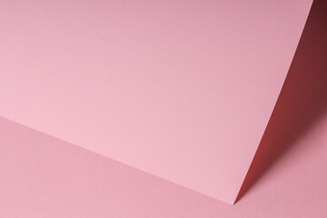 Blank pastel pink paper sheet card note with shadows. Abstract geometric monochrome pink background with copy space for text. Front diagonal view