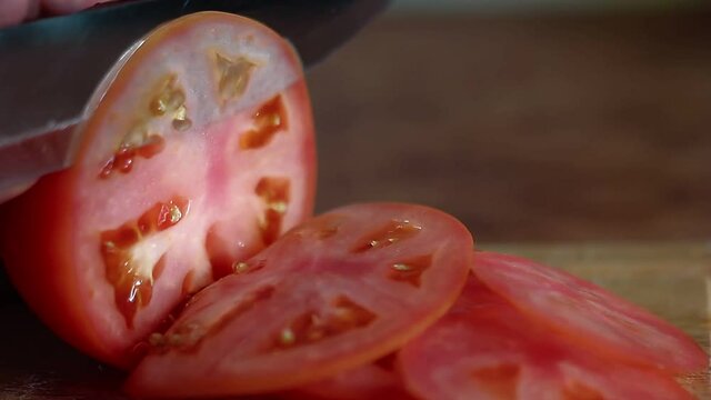 Slicing a fresh ripe tomato to a slices, vegetable food preparing concept