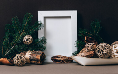 Empty photo frame on brown wall with organic christmas decoration. Styled winter holiday image. Natural christmas home decor. Minimal mockup template.