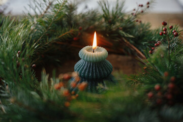 Stylish burning candle in rustic christmas wreath on old wooden background. Moody atmospheric time. Space for text. Christmas advent. Merry Christmas and Happy holidays! Modern xmas tree candle © sonyachny