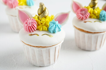Cute sweet unicorn cupcakes on white table, closeup