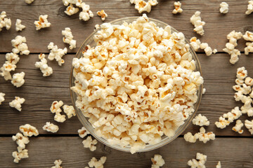 Popcorn in glass bowl on grey wooden background.