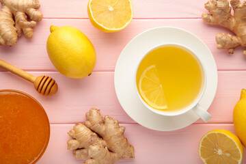 Fototapeta na wymiar Ginger tea with lemon in a white cup on pink wooden background.