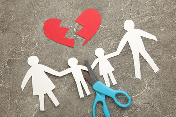 Scissors cutting paper cut of family on grey background. Broken family concept, divorce