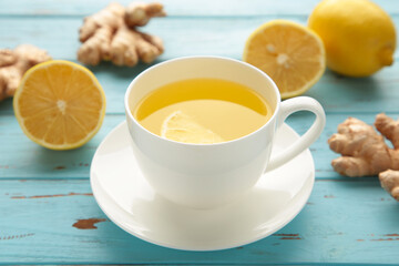 Ginger tea with lemon on blue wooden background.