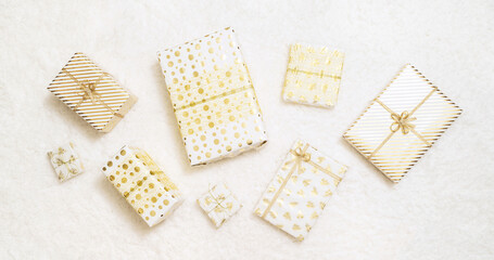 Christmas gifts boxes wrapping  in white gold paper for family lying on fluffy snow-white carpet. Top view