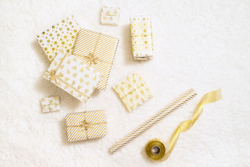 Christmas gifts boxes wrapping  in white gold paper for family lying on fluffy snow-white carpet. Top view
