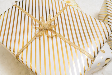Fototapeta na wymiar Close up, cropped of christmas gifts boxes wrapping in white gold paper with bow for family lying on fluffy snow-white carpet. Top view