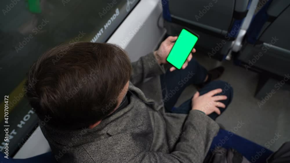 Poster top view of man watch smart phone with green screen and browsing online in train. mock up for watchi