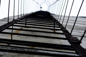 a metal rusty black staircase to the top with thin metal fence bars, looks like a narrow tunnel
