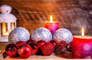 Christmas decoration. A festive lantern against an old wooden wall, surrounded by Christmas balls.