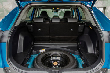 Spare wheel in the trunk of a modern car. Jack lifting and a spare tire in rear of car.