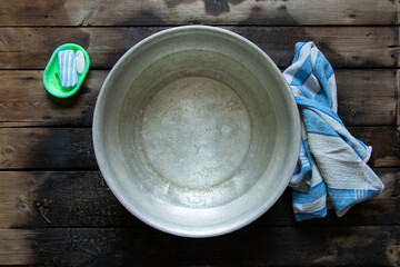 an aluminum bowl with soapy water after washing your feet is on the floor next to soap and a towel,...