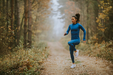 Fototapeta na wymiar Young woman running having exercise on forest trail at autumn