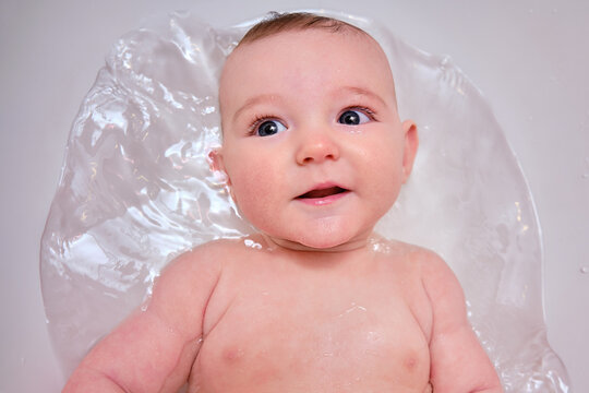 Portrait of an infant baby lying in a children bath. A baby at the age of four months bathes in water