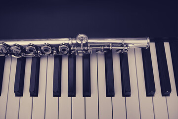 A large concert transverse flute lies on the piano keys © Андрей Журавлев
