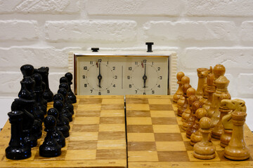 Chessboard with pieces in the starting position and with a clock showing the time of the game