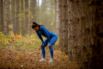 Young woman take a break during outdoor exercise on the forest trail at autumn