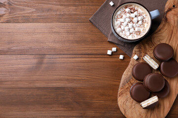 Tasty choco pies and cocoa with marshmallows on wooden table, flat lay. Space for text