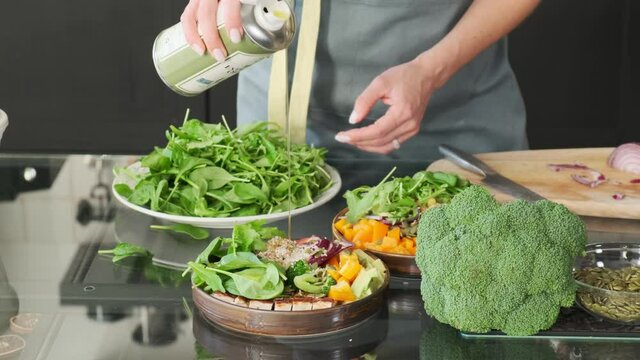 The chef pours the salad with extra virgin olive oil. Close-up. A jar of olive oil in the hands of a girl. Russia, Rostov-on-Don, 12 Nov 2021 
